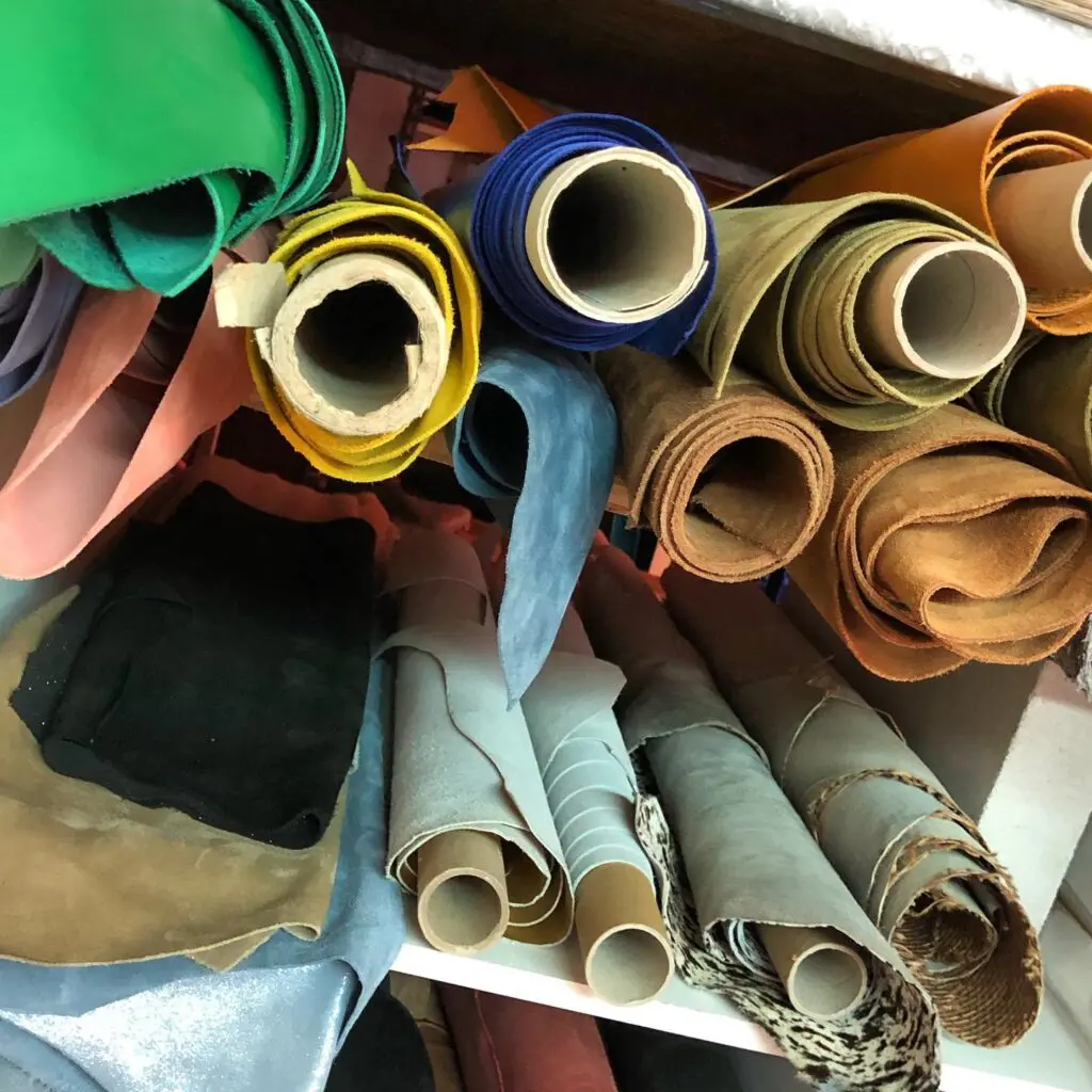Rouleaux de cuir colorés empilés sur des étagères, utilisés pour la fabrication d'articles en cuir.