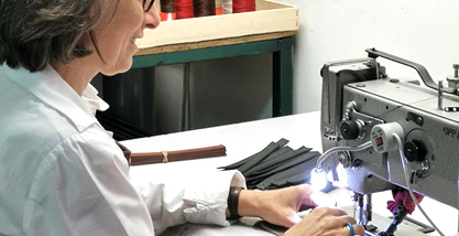 Personne utilisant une machine à coudre industrielle, travaillant sur des pièces de tissu dans un atelier de couture.