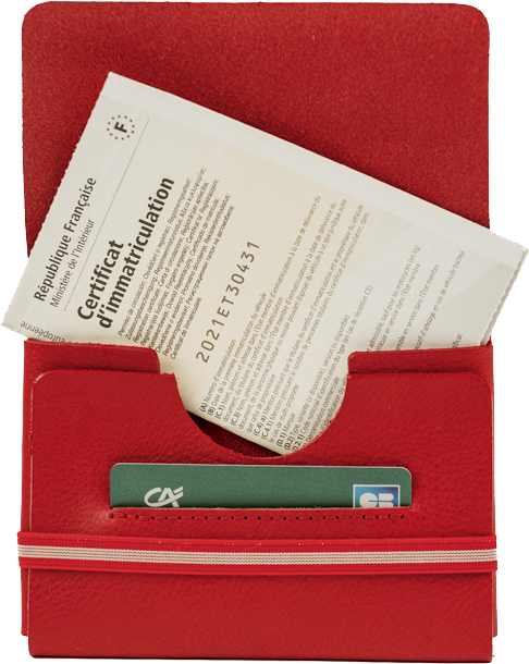 Certificat d'immatriculation français dans un étui rouge avec une carte bancaire visible en dessous.